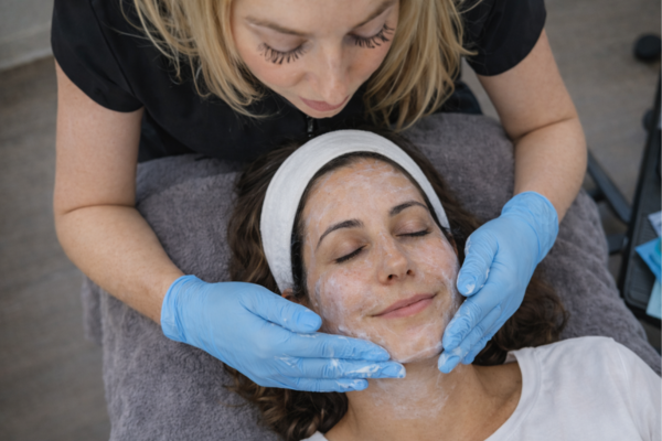 Medical facial treatment at Revelus Dermatology in Austin with cleanser application and headband