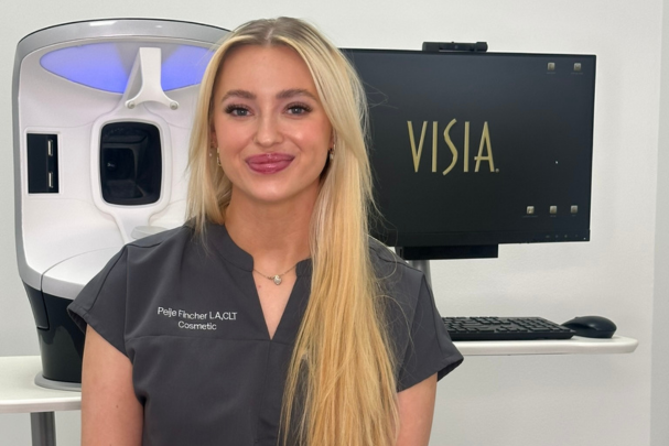 Aesthetician Peije Fincher sitting next to Visia Skin Analysis machine.